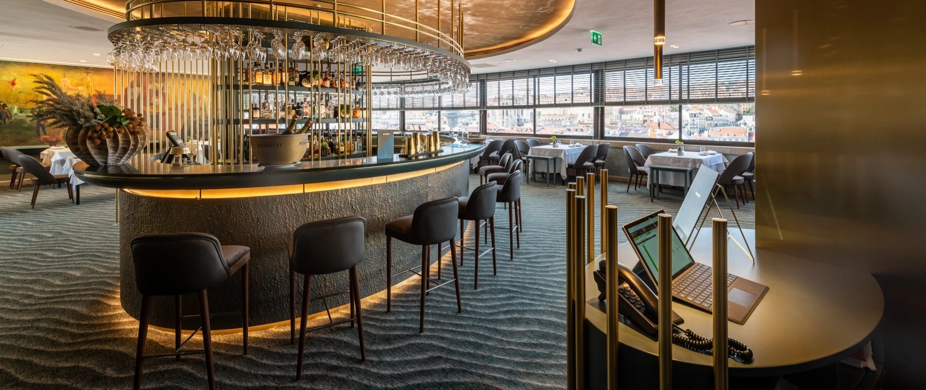 Bar des Restaurants mit beleuchteter Theke, Gl&auml;sern und Blick auf die Stadt