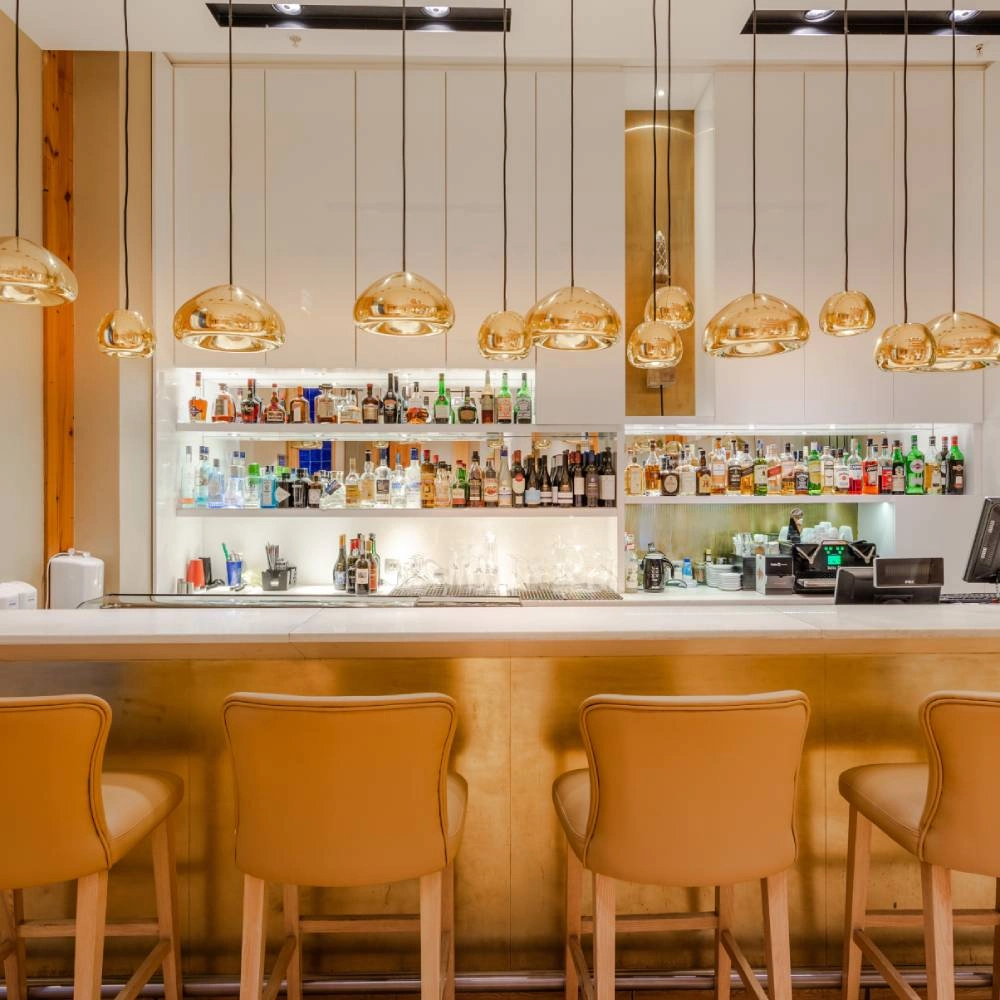 Bar with counter, liquor shelves, and hanging golden lamps
