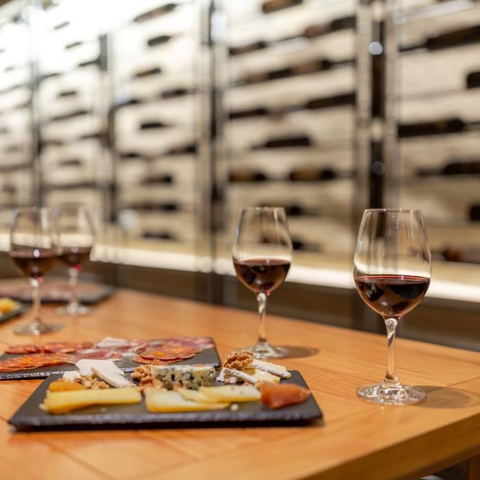 Ta&ccedil;as de vinho tinto e t&aacute;bua de petiscos &agrave; mesa, com luz natural