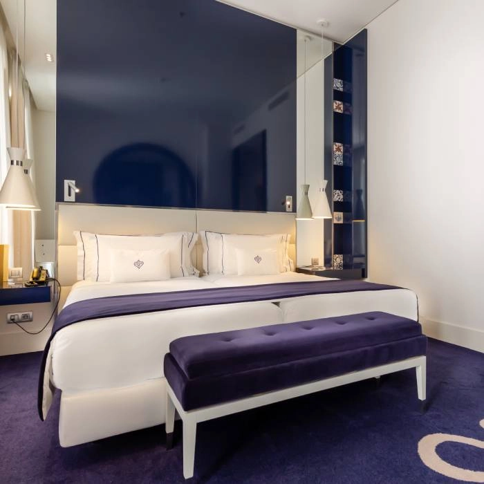 Quarto moderno com cama king, poltrona azul e parede espelhada