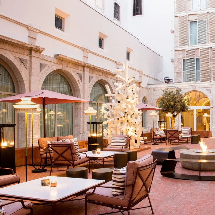 Hotel patio with tables, chairs, and orange umbrellas at sunset