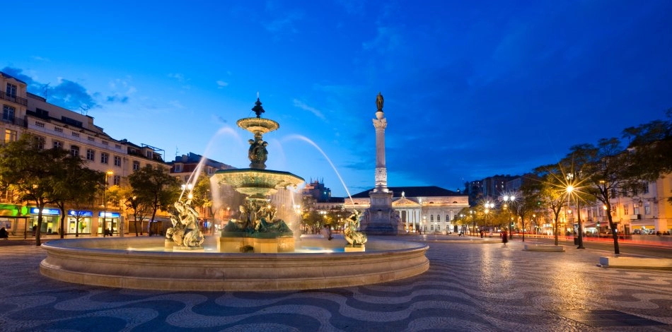 Fountain illuminated and monument in square at night, with blue sky