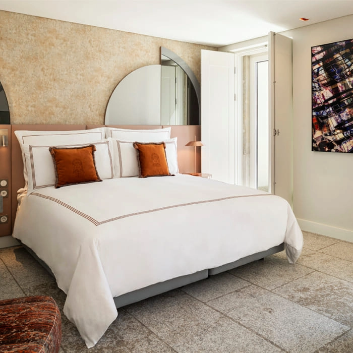Modern room with white king bed and orange pillows, beige wall