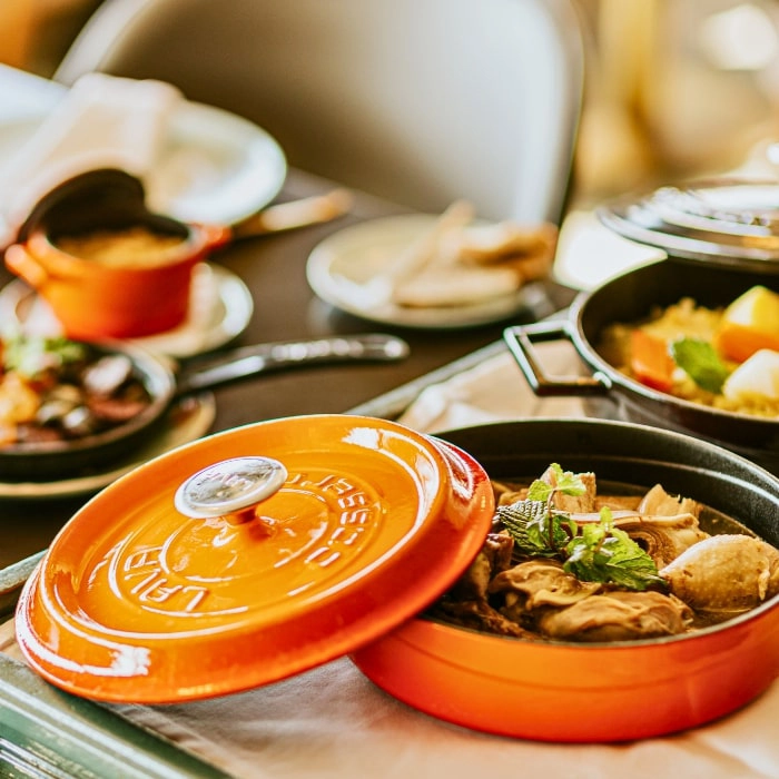 Meal in orange plates and tureens with meat and vegetables, set table