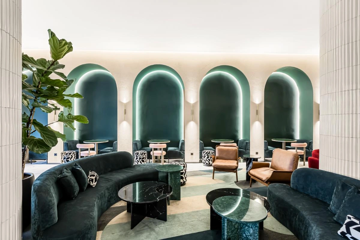 Sala moderna com sof&aacute;s escuros, poltronas e arcos verdes com ilumina&ccedil;&atilde;o LED.