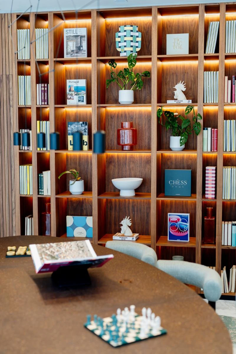 Sala de leitura com estante de livros e pe&ccedil;as de xadrez sobre mesa