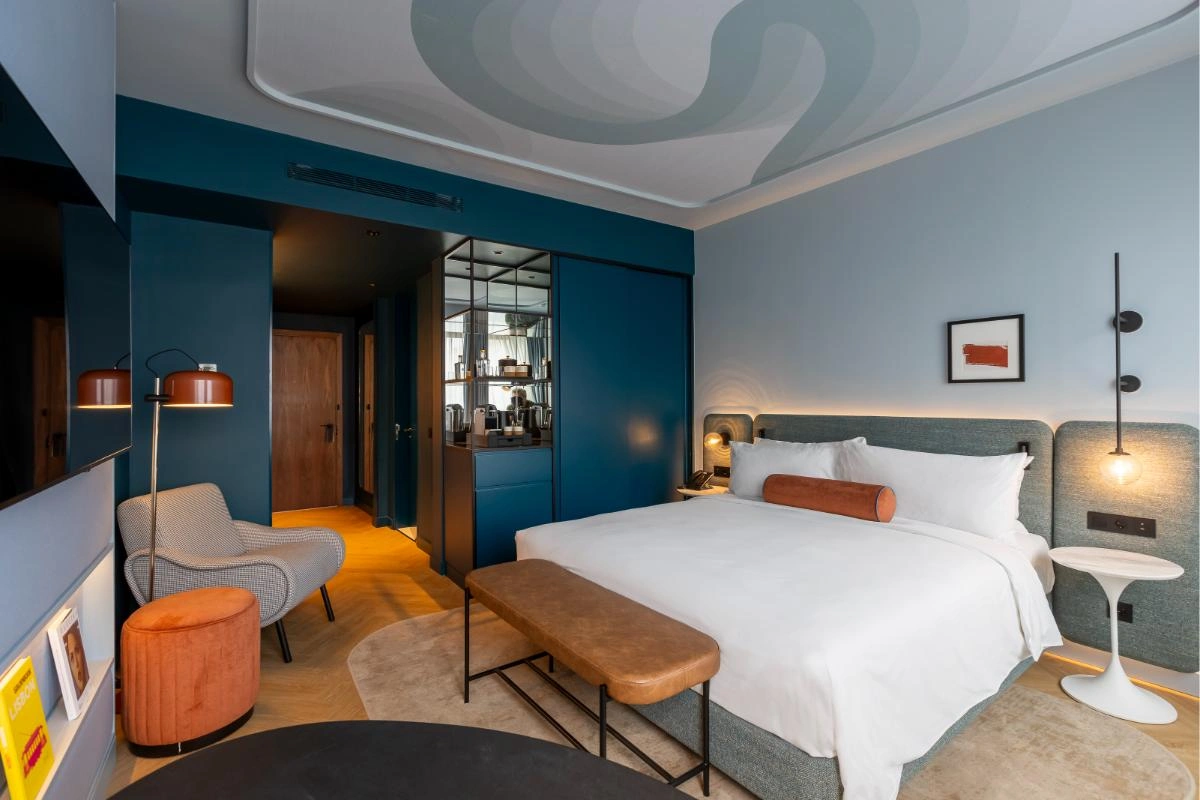 Quarto de hotel moderno com cama king, poltrona e luzes aconchegantes