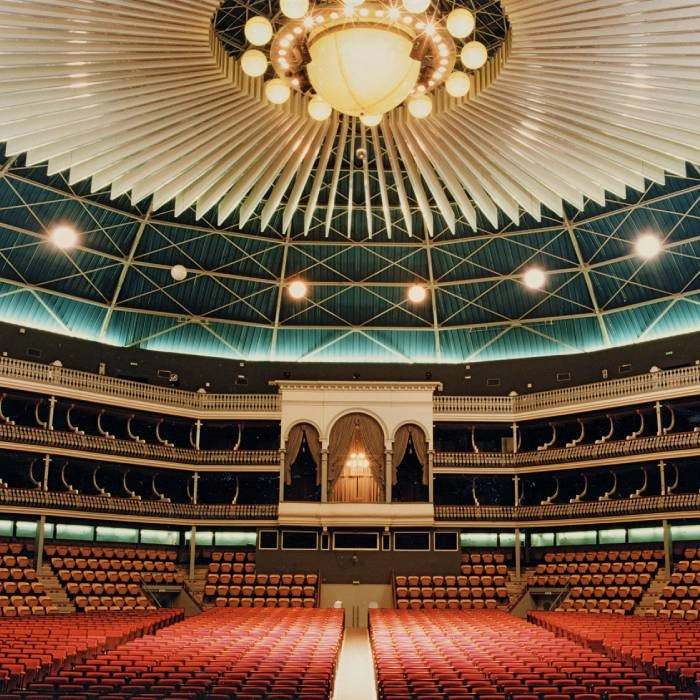 Interior de teatro con gradas, escenario y luces en el techo