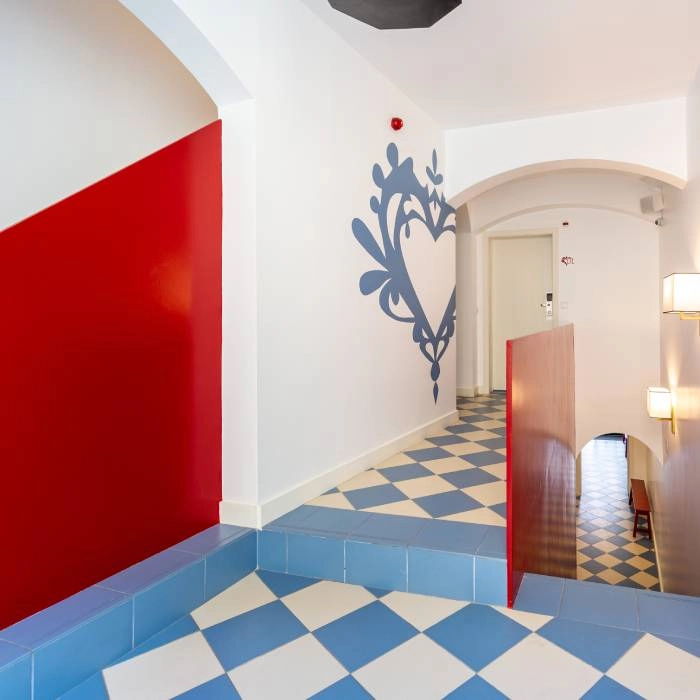 Corredor com piso xadrez azul e branco e parede com adesivo floral.