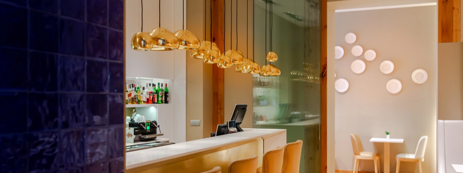 Bar mit Theke, St&uuml;hlen und goldener H&auml;ngelampe in moderner Umgebung