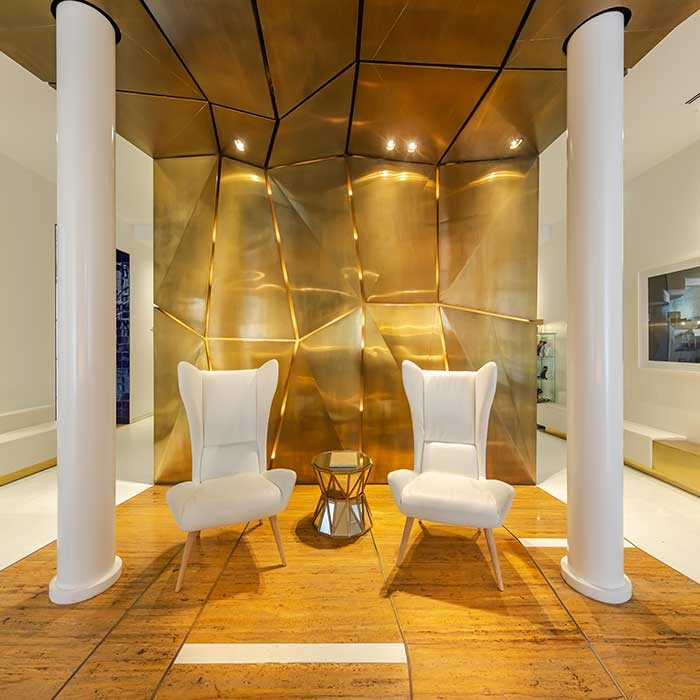 Moderne Wohnzimmer mit zwei wei&szlig;en Sesseln, Couchtisch und goldener Wand