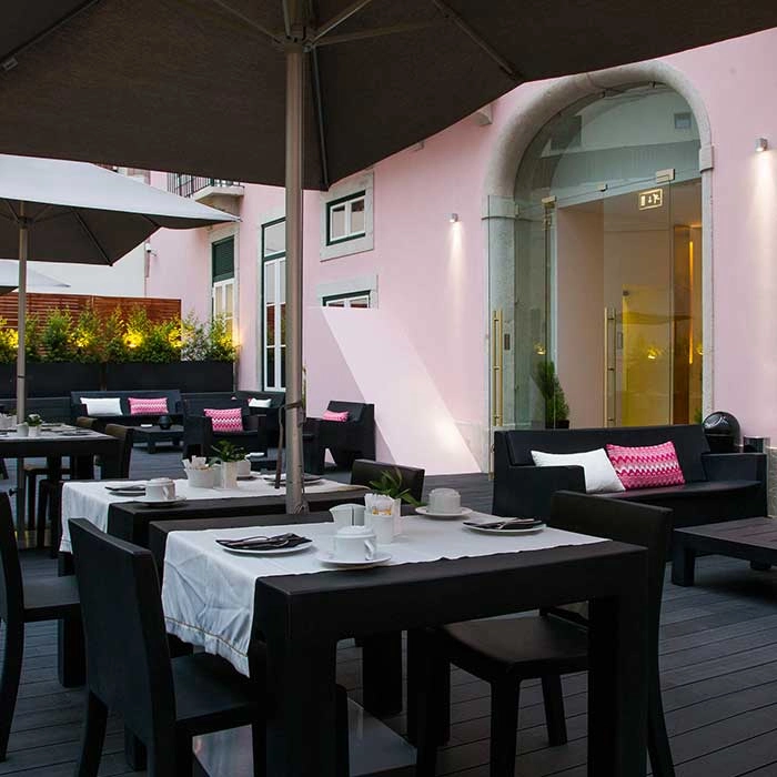Au&szlig;enbereich mit Tischen und St&uuml;hlen unter Sonnenschirmen auf modernem Patio