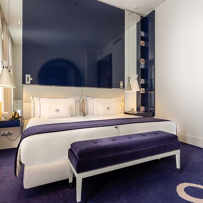 Modernes Schlafzimmer mit Kingsize-Bett, blauer Bettw&auml;sche und eleganter Beleuchtung
