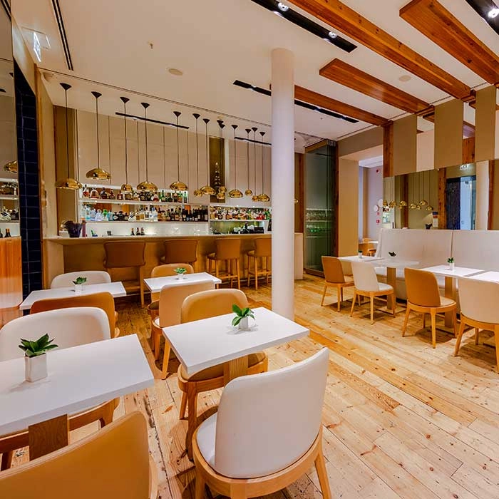 Restaurant-Salon mit wei&szlig;en Tischen und St&uuml;hlen, Theke und h&auml;ngenden Lampen