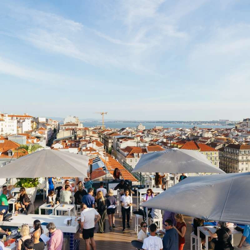 Rooftop view with people, umbrellas, and the sea in the background