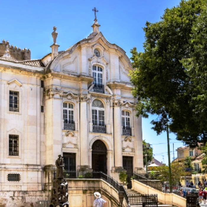 Fachada hist&oacute;rica con columnas y &aacute;rboles al fondo, en Portugal