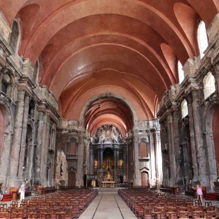 Interior de iglesia con b&oacute;veda de arcos y bancos de madera al fondo