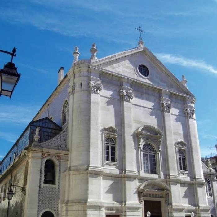 Fachada de iglesia blanca con c&uacute;pulas y cruz en la cima bajo cielo azul