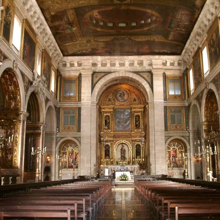 Interior de iglesia con altar dorado y bancos de madera en el centro