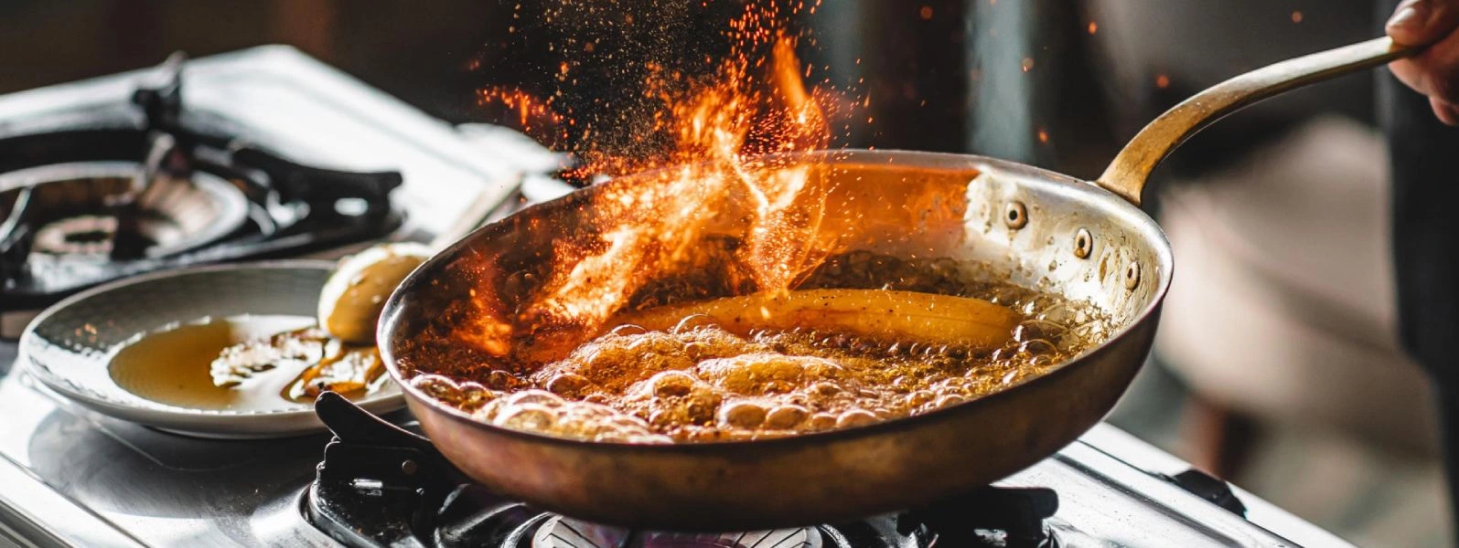 Panela no fogo com &oacute;leo fervendo e chamas, preparo de fritura em cozinha industrial
