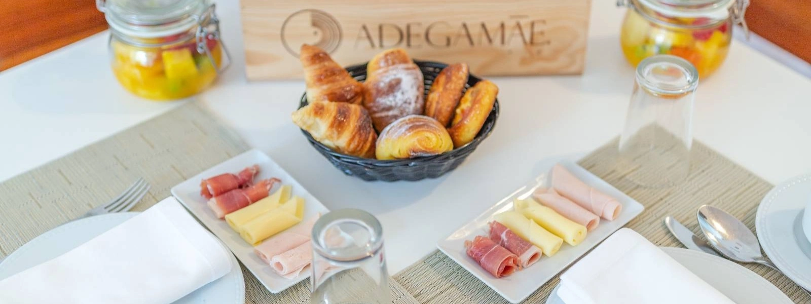 Caf&eacute; da manh&atilde; com p&atilde;es, frios e queijos em mesa posta