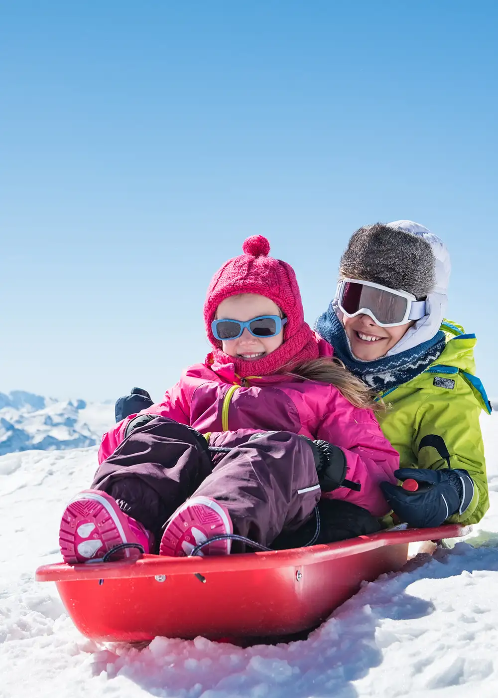 Personas esquiando en trineo rojo en la nieve, con cascos y gafas.