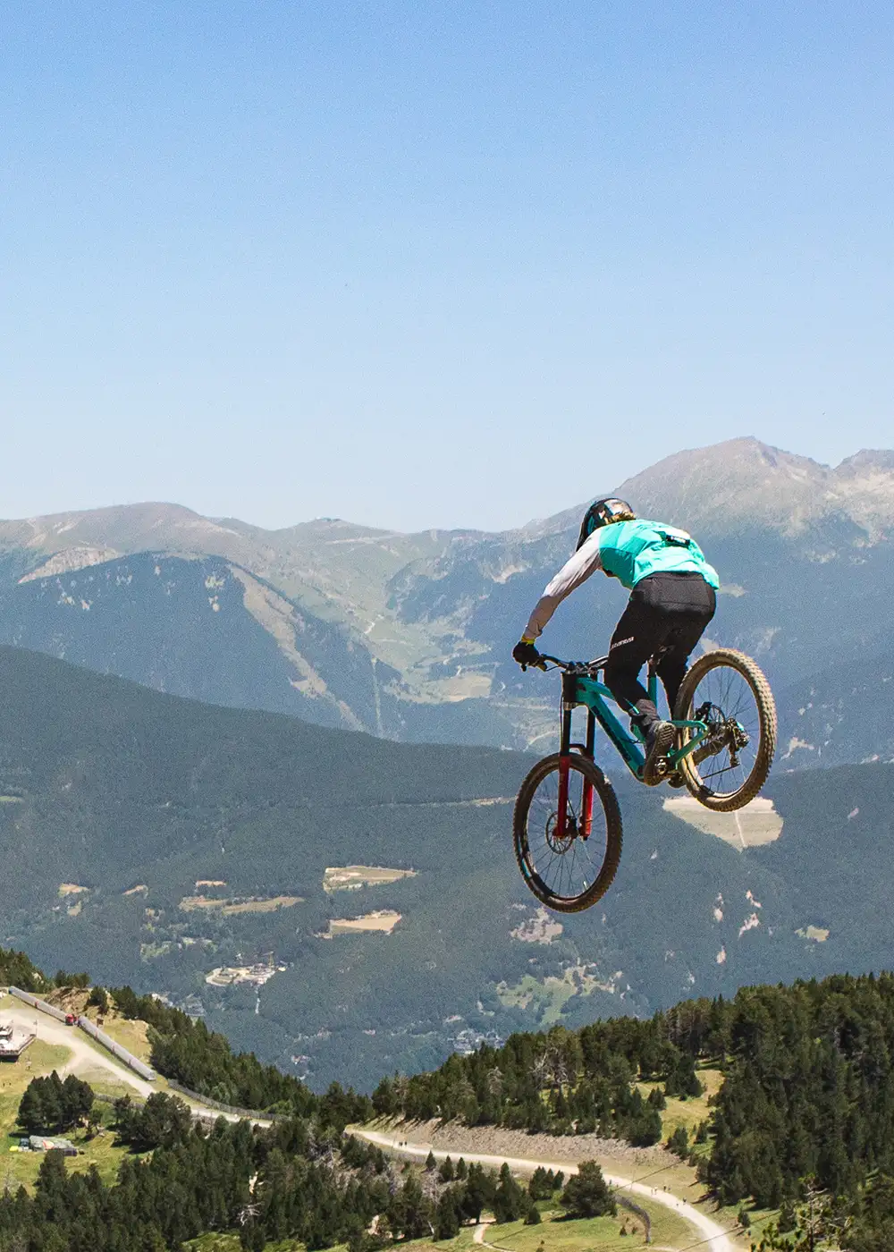 Ciclista hace un salto en bicicleta de monta&ntilde;a sobre un valle monta&ntilde;oso.