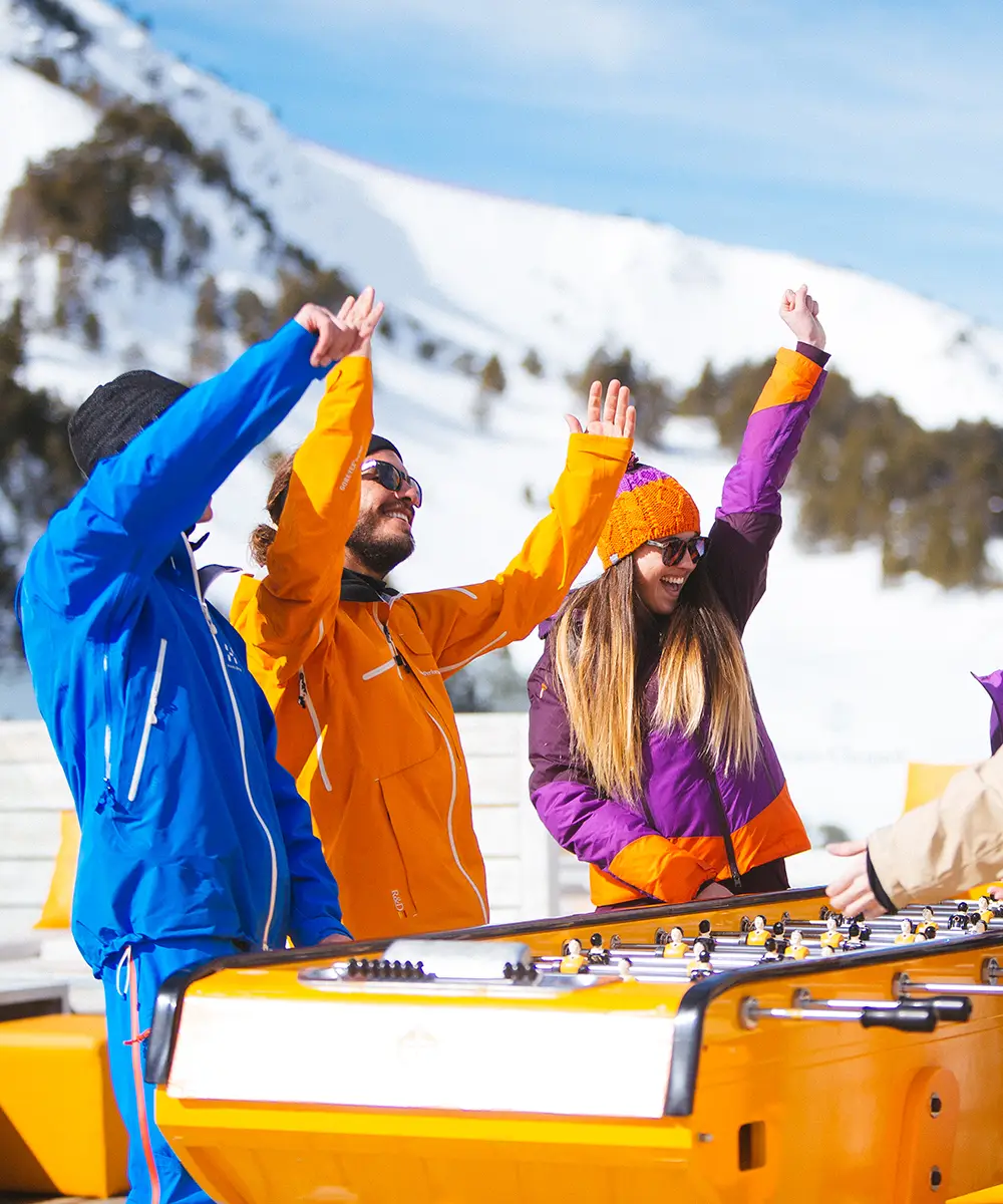 Tres esquiadores con ropa de invierno levantan las manos sobre un trineo en nieve