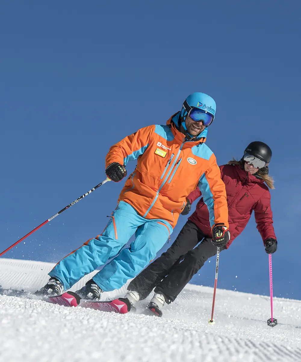 Esquiadores descienden juntos en la nieve, con casco y bastones.
