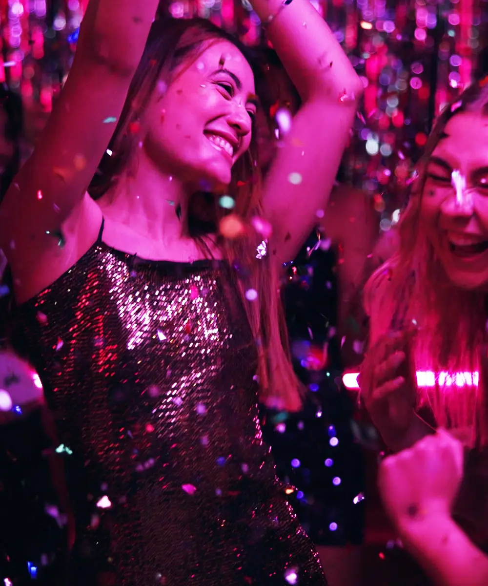 Mujer con vestido brillante, fiesta con confeti rosa y luces ne&oacute;n, sonriendo