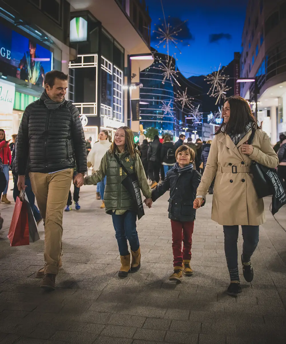 Familia caminando en una calle comercial iluminada con fuegos artificiales de fondo