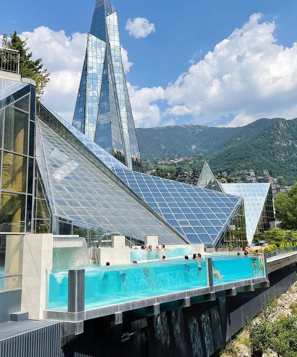 Piscina exterior con agua turquesa y rascacielos de cristal al fondo en monta&ntilde;a