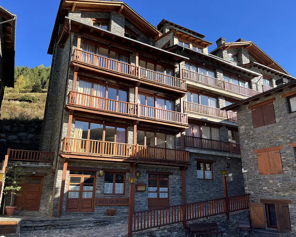 Fachada de un edificio de piedra con balcones de madera y restaurante.