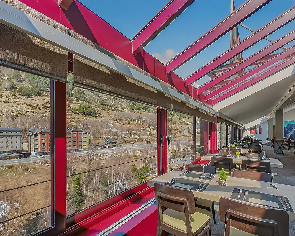 Terraza con mesas y barandal rojo, vista a la monta&ntilde;a y valle desde un hotel