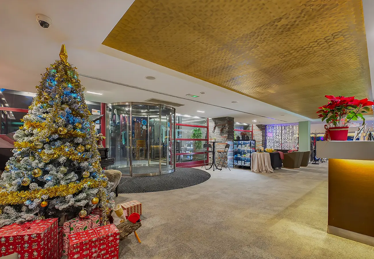 &Aacute;rbol de Navidad decorado y recepci&oacute;n con cortina de luz en un lobby interior
