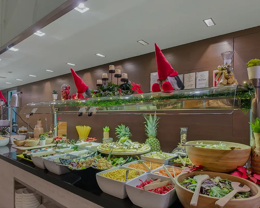 Buffet de ensaladas con decoraciones navide&ntilde;as y sombreros rojos de duende
