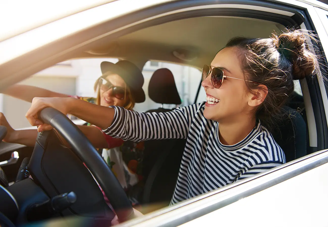 Mujer sonriente conduce coche y disfruta el viaje con gafas de sol