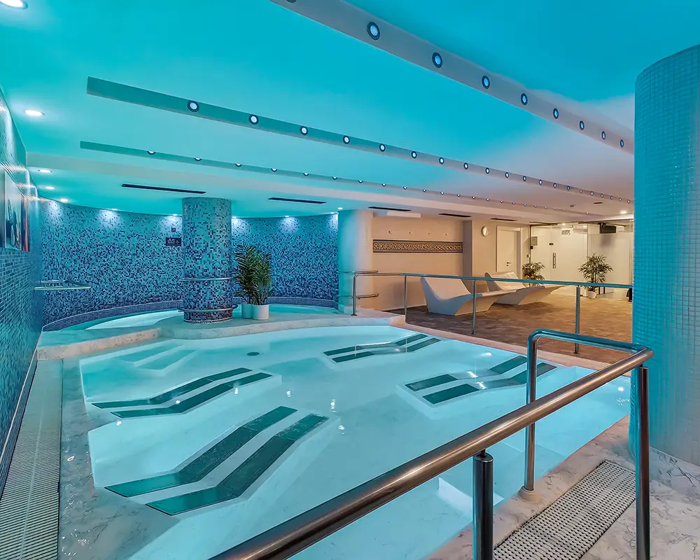 Piscina interior de spa con luces y azulejos azules.