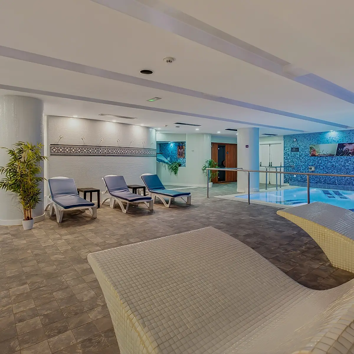 Terraza interior con piscina, tumbonas y paneles azules y blancos
