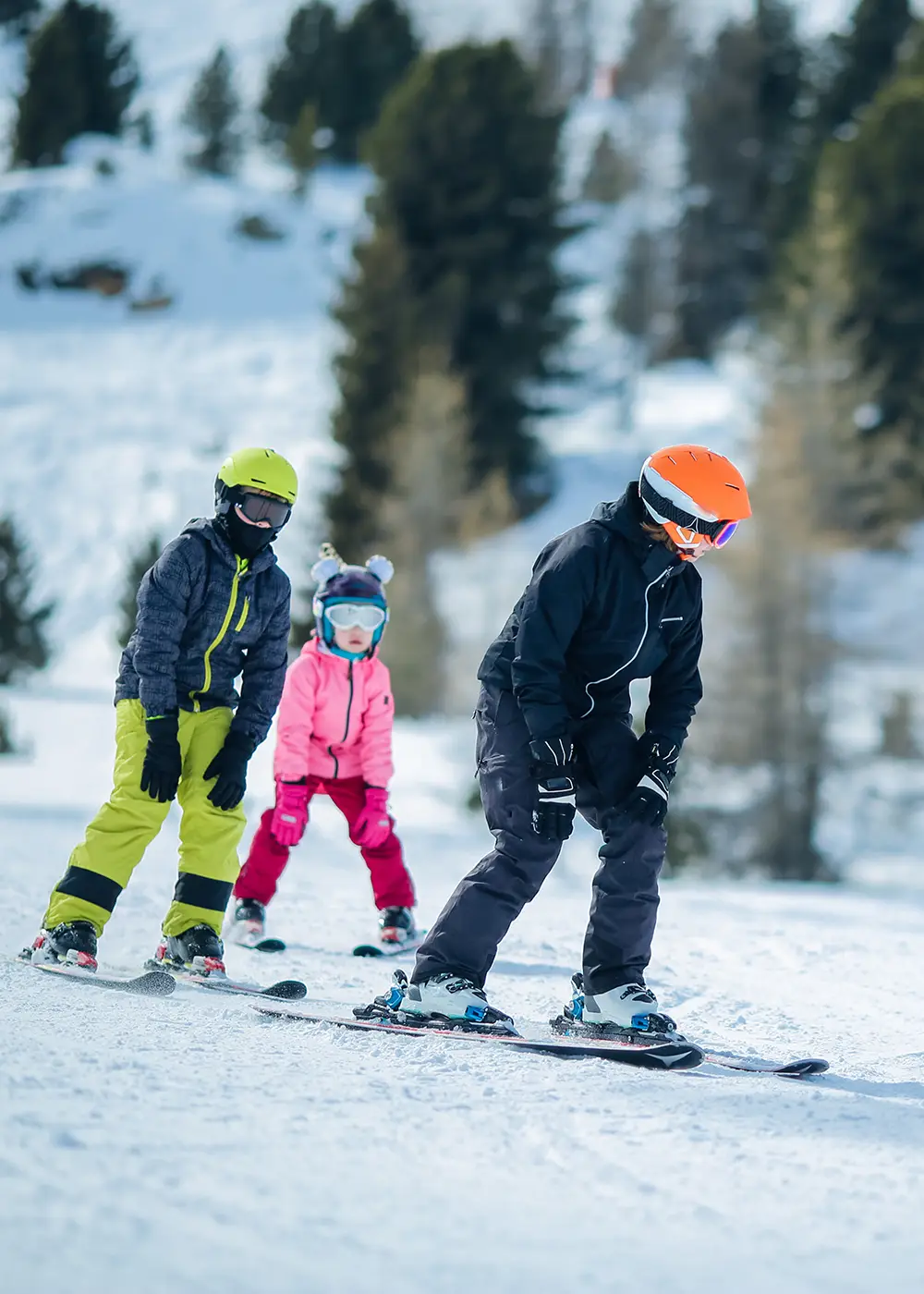 Ni&ntilde;os esquiando en la nieve con cascos y tablas, en una pista alpina