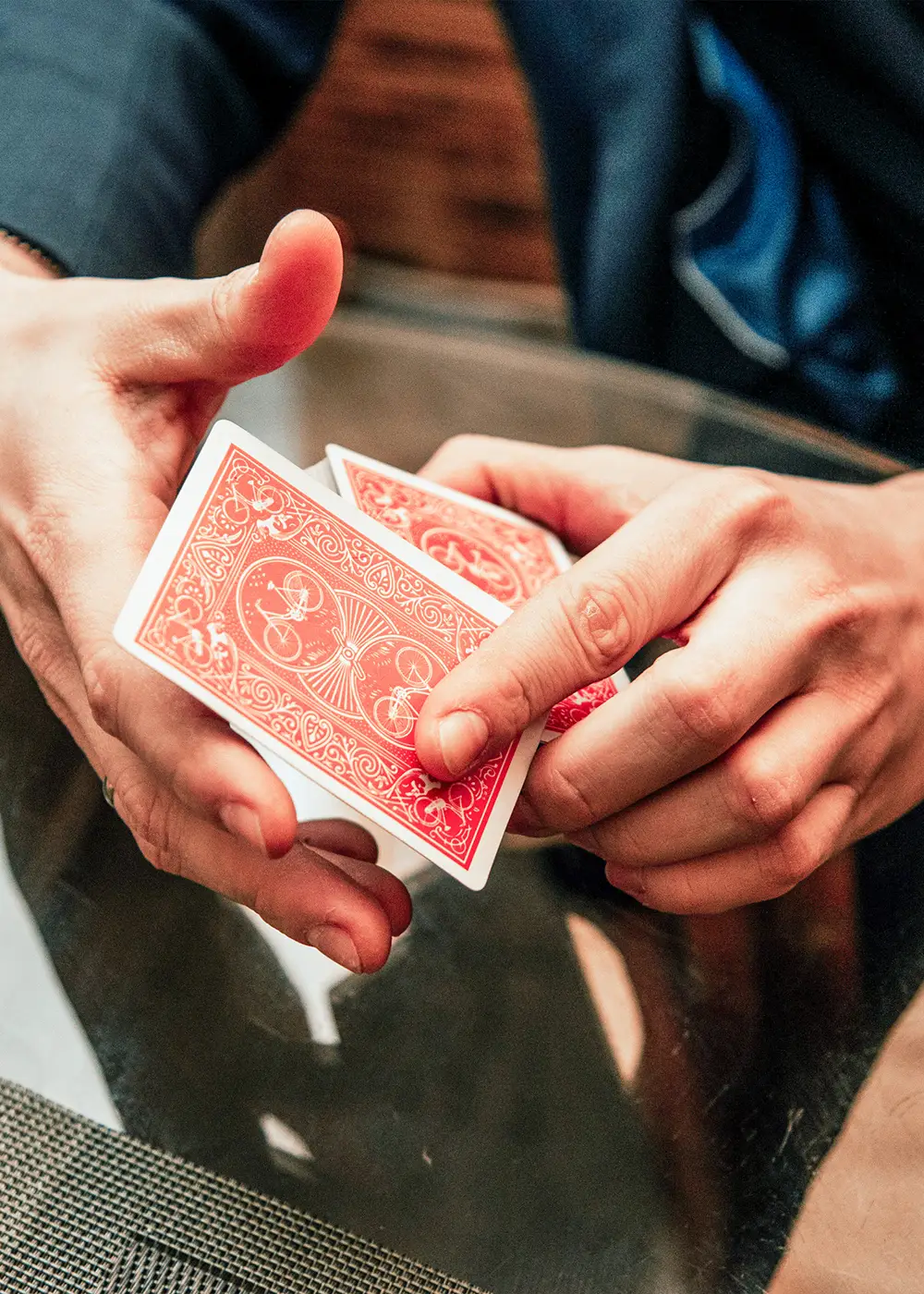 Manos barajando cartas rojas de p&oacute;ker en una mesa
