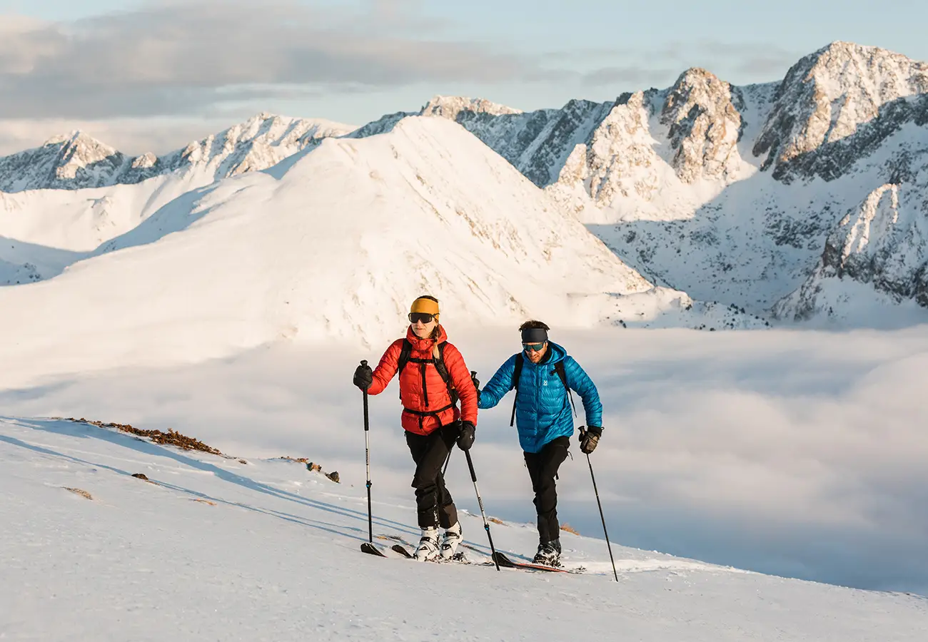 Dos esquiadores con bastones en la nieve, frente a monta&ntilde;as nevadas