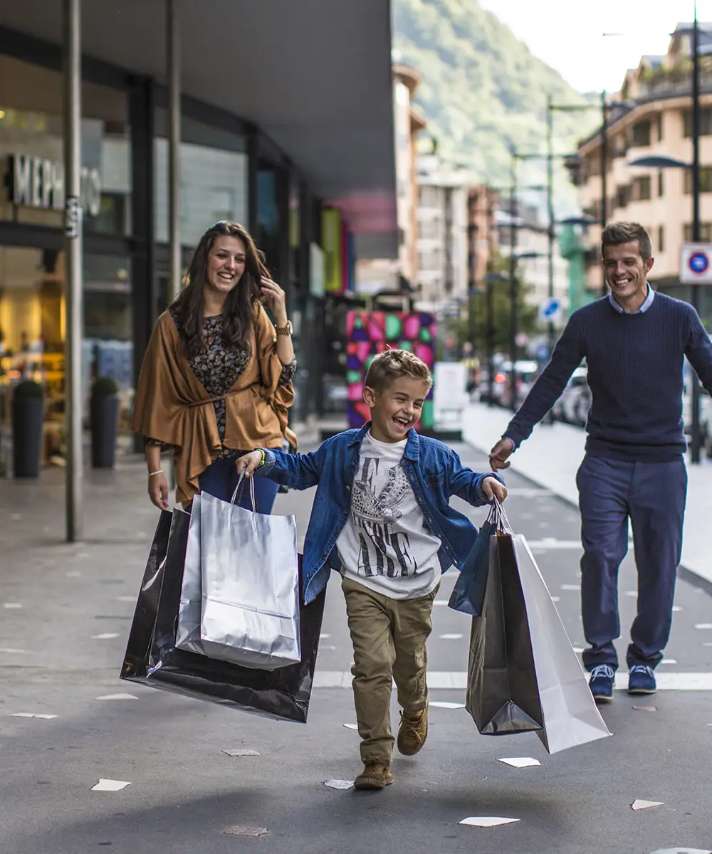 Familia paseando por la calle con bolsas de compras, ni&ntilde;o feliz al frente