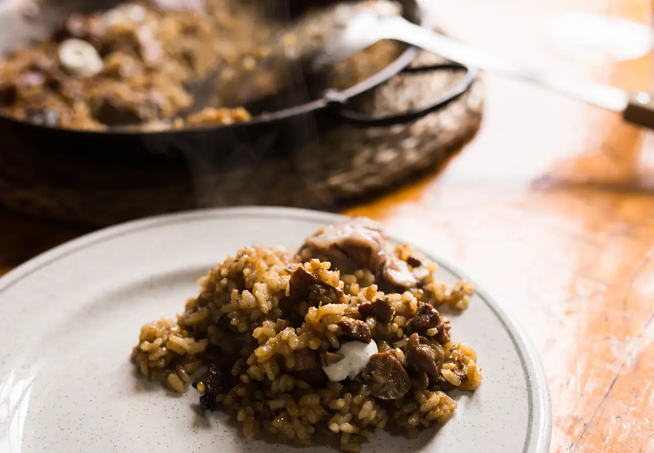 Arroz con verduras en plato blanco, con sart&eacute;n borrosa al fondo