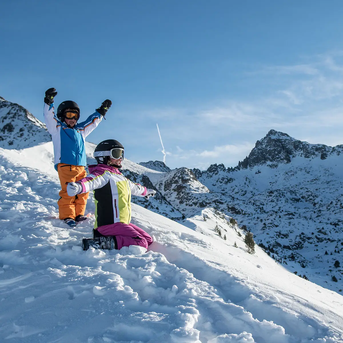 Esquiadores en la nieve con monta&ntilde;as nevadas al fondo, celebrando.