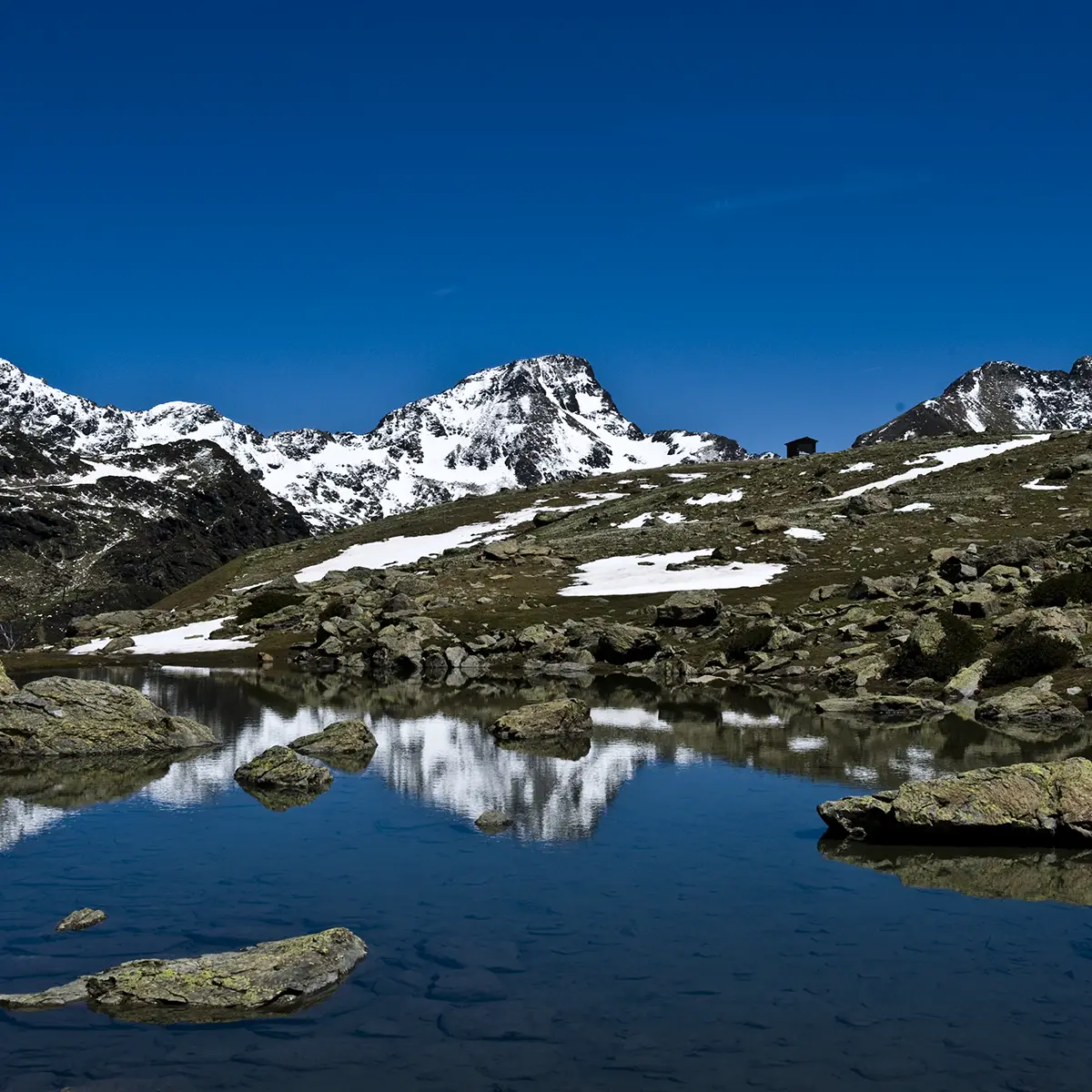 Monta&ntilde;as nevadas y lago azul reflejando el paisaje bajo cielo despejado