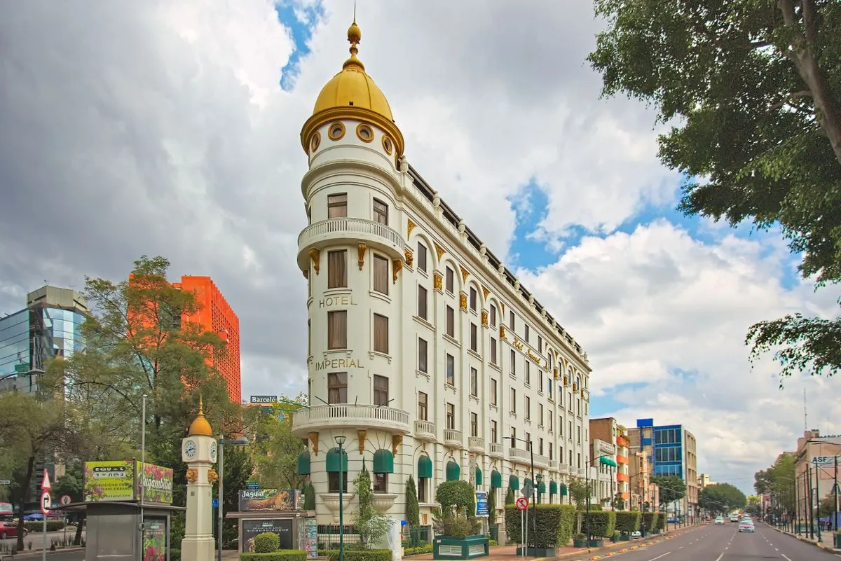 Fachada del Hotel Imperial con c&uacute;pula dorada y avenida arbolada