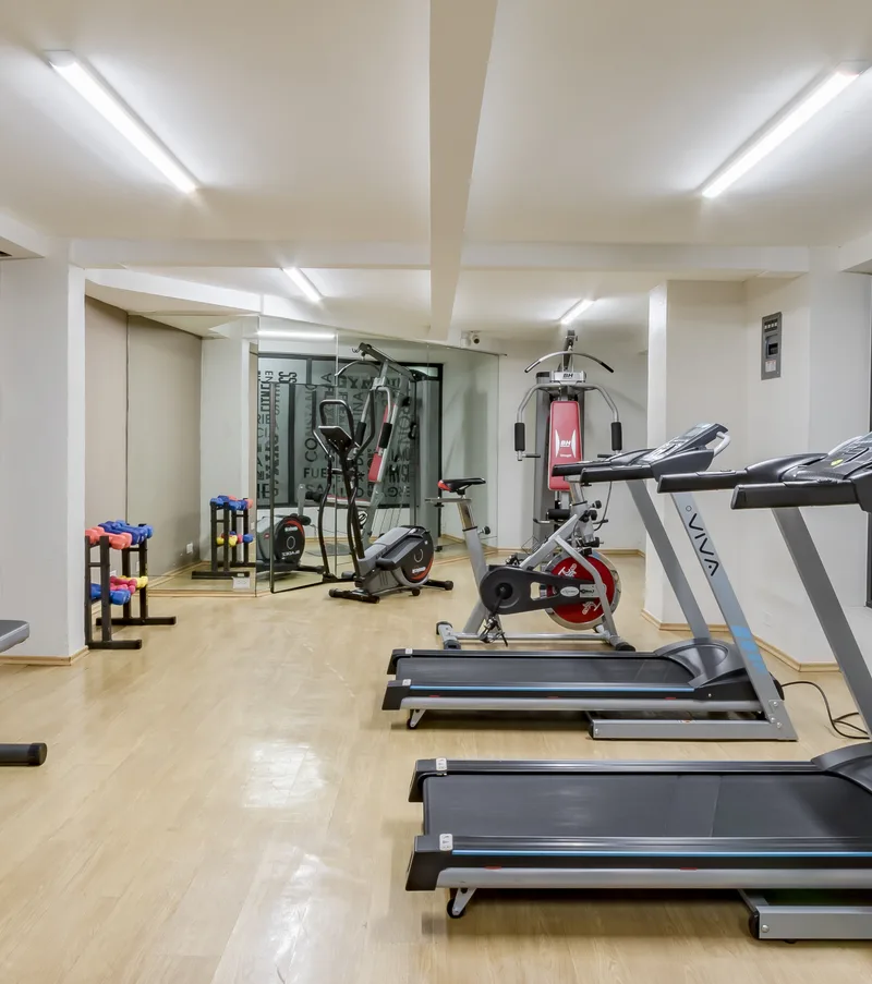 Gimnasio con m&aacute;quinas cardiovasculares y pesas en sala luminosa