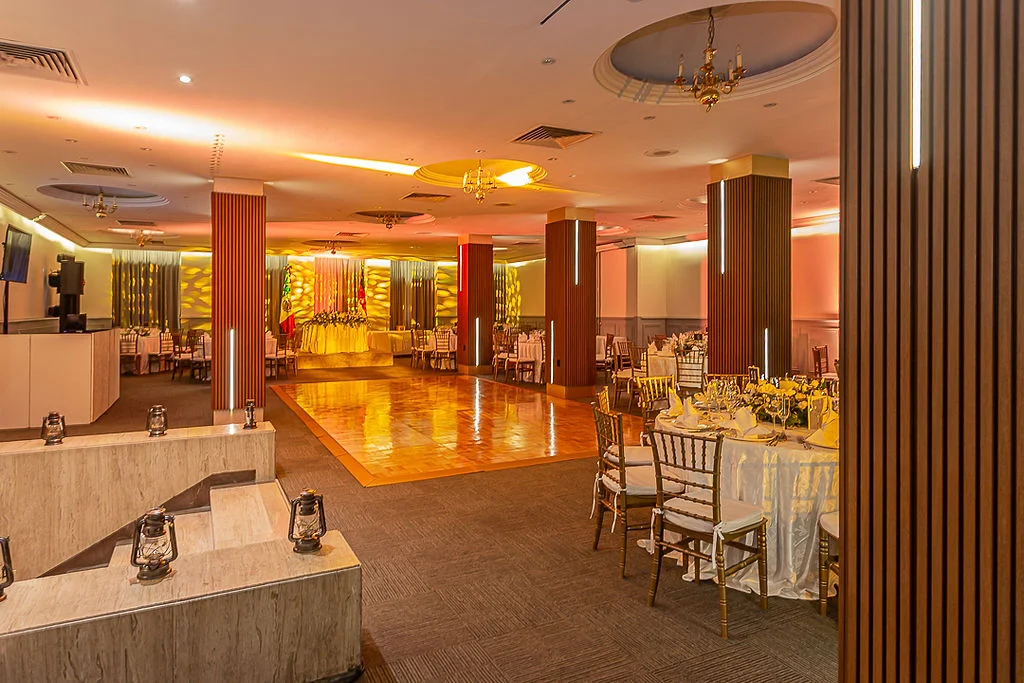 Sal&oacute;n de eventos elegante con mesas, sillas y candelabros dorados.