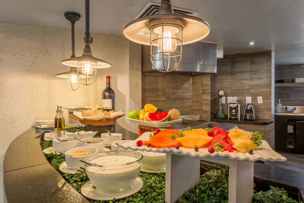 Mesa con barra de ensaladas y luces colgantes en cocina hotelera
